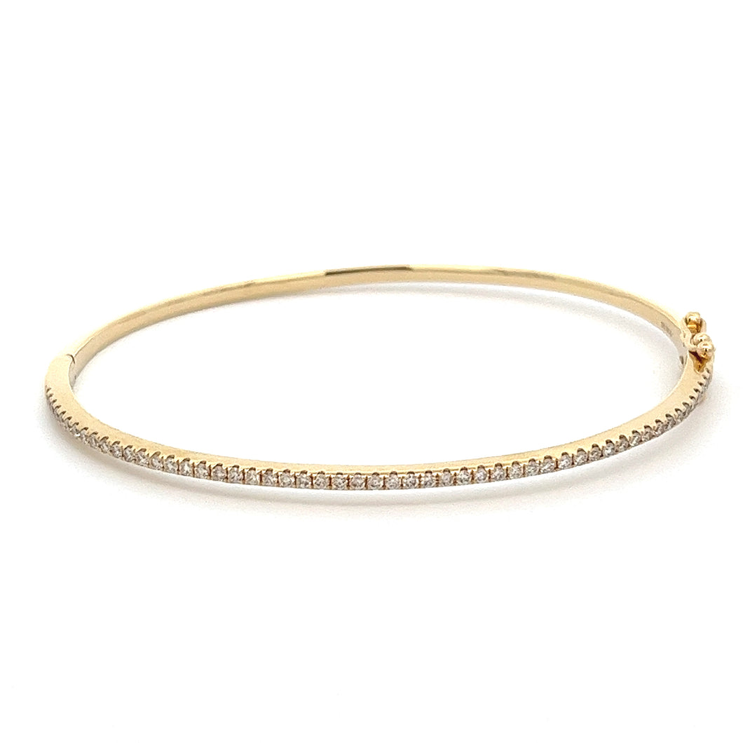 This 14k yellow gold diamond bangle features round brilliant cut di...