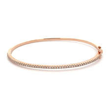 This 14k rose gold diamond bangle features round brilliant cut diam...