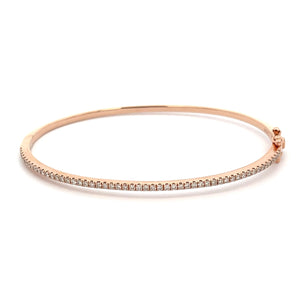 This 14k rose gold diamond bangle features round brilliant cut diam...